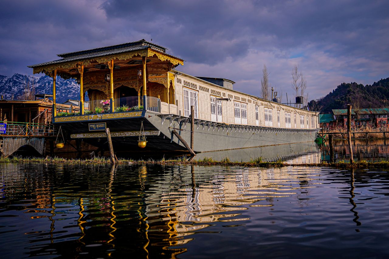 The Art of Drawing Readers In: Your attractive post title goes here Scenic view of a traditional houseboat on Dal Lake, Srinagar under a vivid sky reflecting in calm waters.