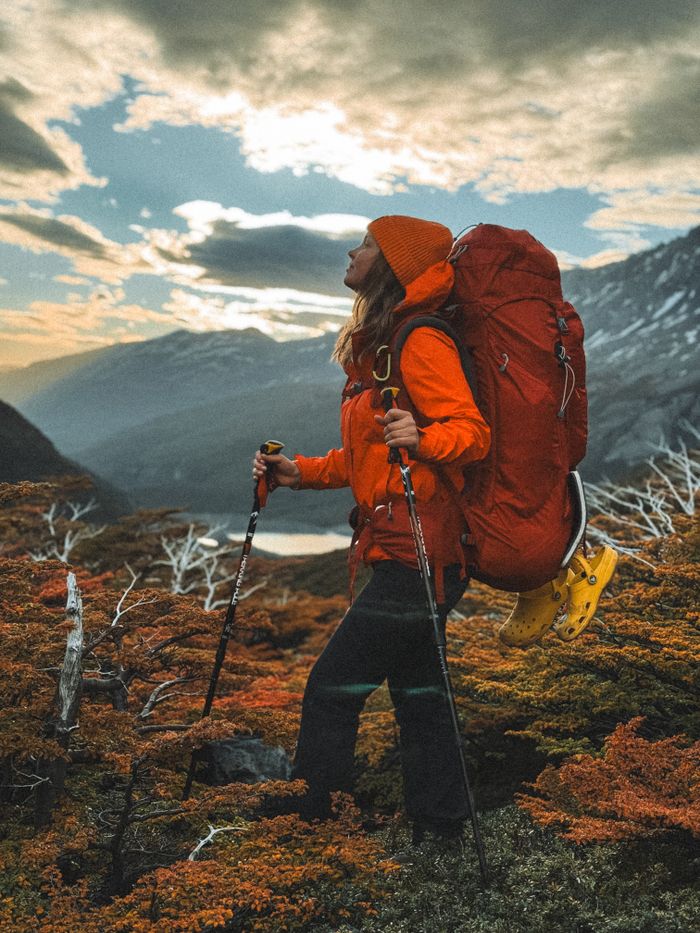 A woman hiker enjoys a scenic sunset view in Magallanes, Chile with vibrant autumn colors.